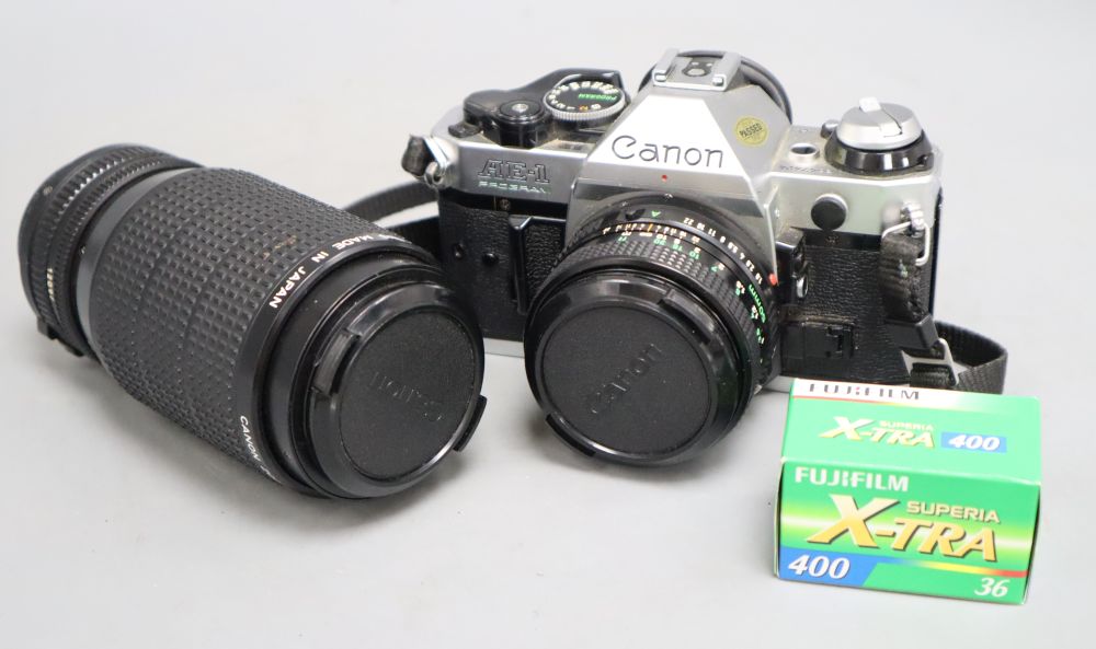 A cased Canon AE-1 programme camera with a 50mm lens, together with a 75-200mm zoom lens, also Canon accessories